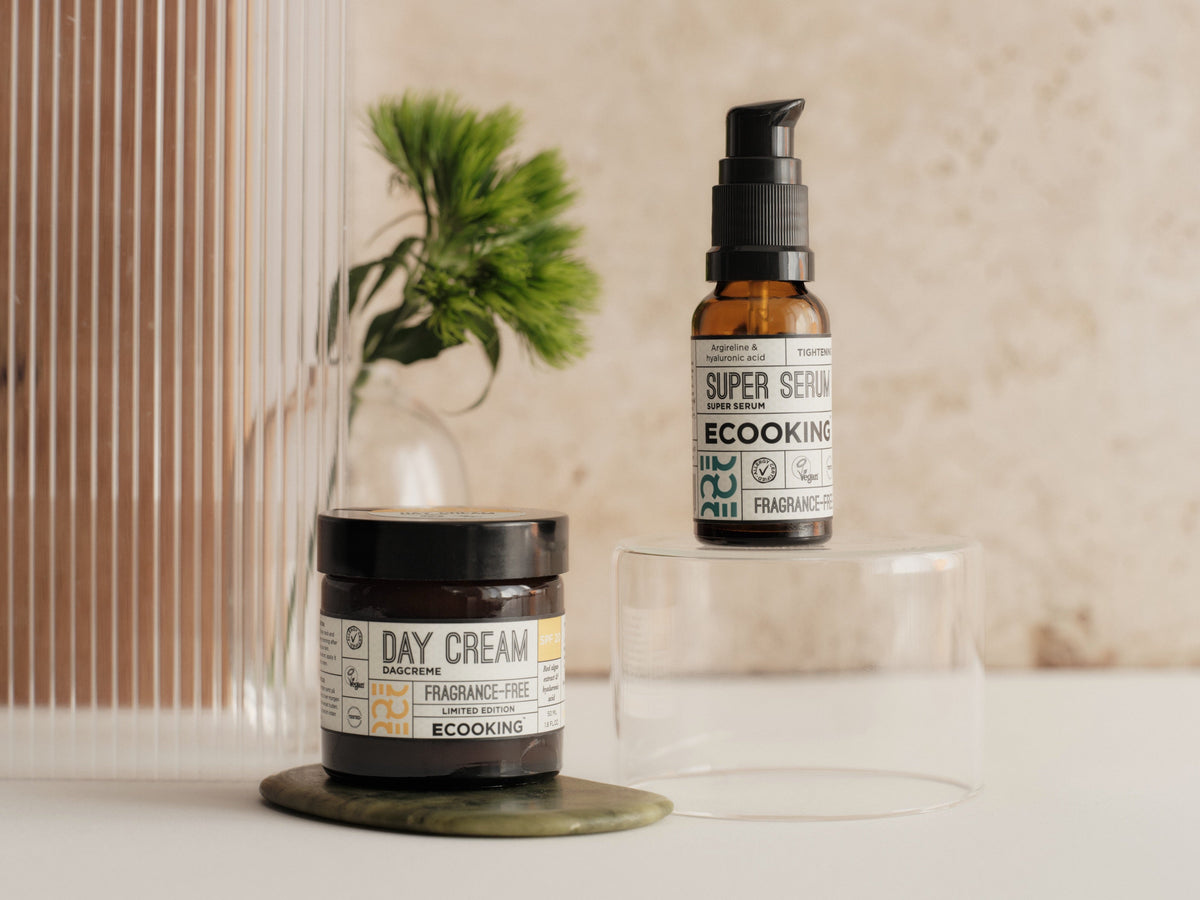 Dagcreme og Super Serum med en grøn blomst på beige: roligt studiolys.