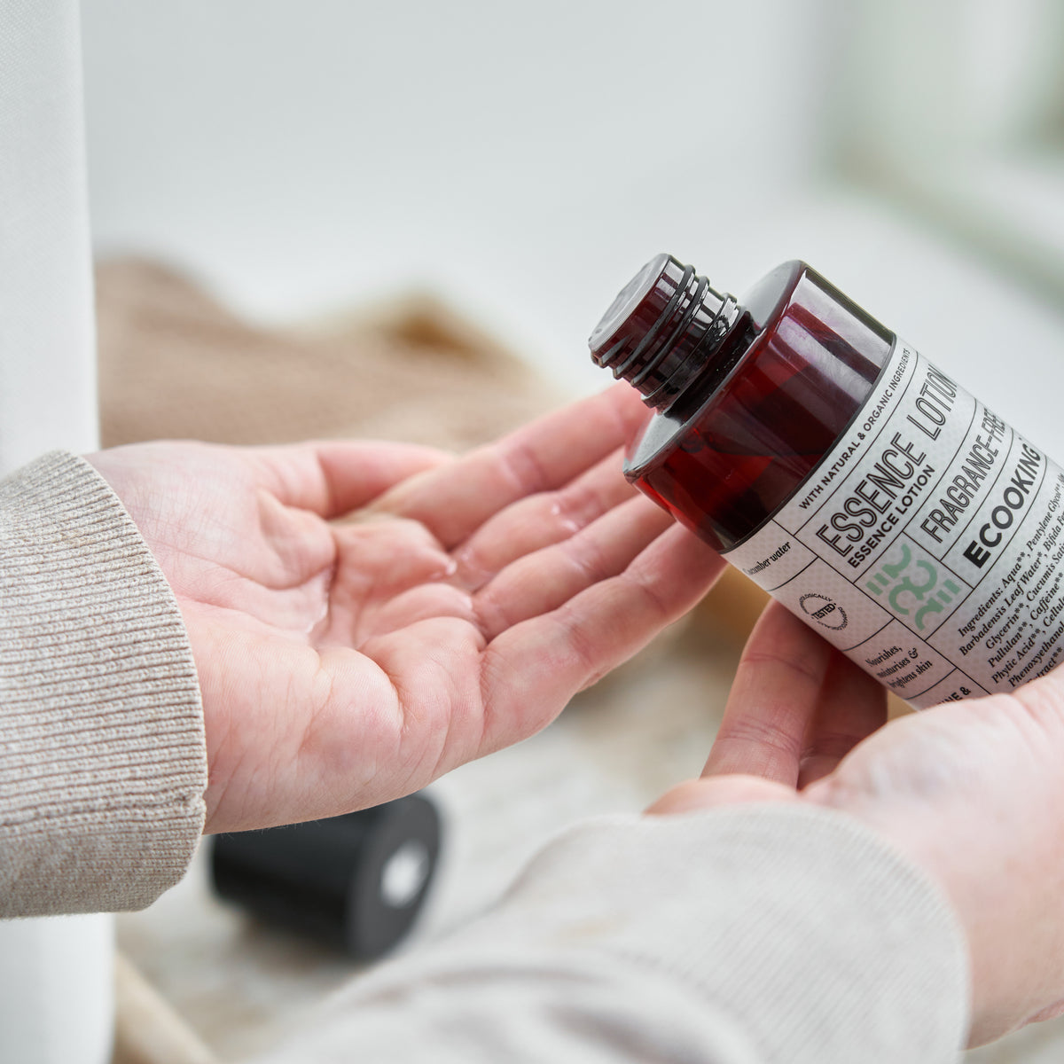 Hænder, der hælder Essence Lotion ud i håndfladen – essence og fugtgivende toner i ét, der giver glød