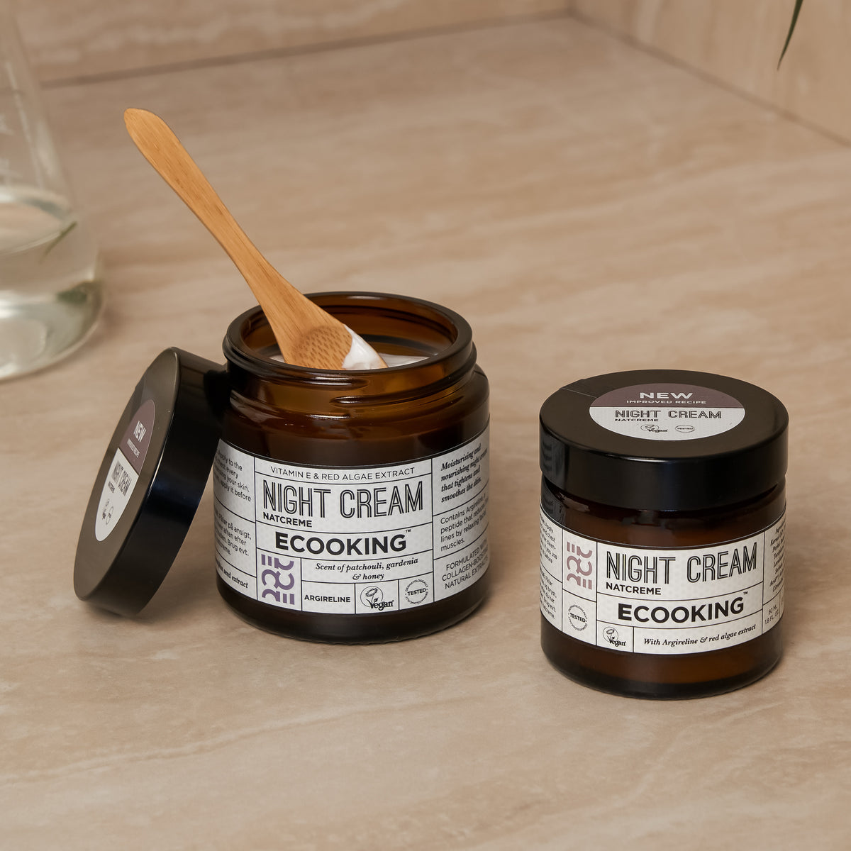 To krukker ECOOKING Natcreme på en badeværelseshylde, den ene åben med en træspatel – natcreme mod rynker og fine linjer, der fugter og giver glød